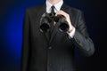 Business and search topic: Man in black suit holding a black binoculars in hand on a dark blue background in studio isolated Royalty Free Stock Photo