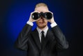 Business and search topic: Man in black suit holding a black binoculars in hand on a dark blue background in studio isolated Royalty Free Stock Photo