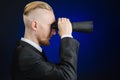 Business and search topic: Man in black suit holding a black binoculars in hand on a dark blue background in studio isolated Royalty Free Stock Photo