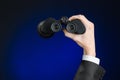 Business and search topic: Man in black suit holding a black binoculars in hand on a dark blue background in studio isolated Royalty Free Stock Photo