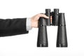 Business and search topic: Man in black suit holding a black binoculars in hand on white isolated background in studio Royalty Free Stock Photo