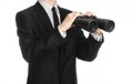 Business and search topic: Man in black suit holding a black binoculars in hand on white isolated background in studio Royalty Free Stock Photo