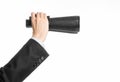 Business and search topic: Man in black suit holding a black binoculars in hand on white isolated background in studio Royalty Free Stock Photo