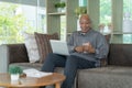 Business senior old elderly Black American man, African person using a smartphone or mobile phone in living room at home in Royalty Free Stock Photo