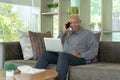 Business senior old elderly Black American man, African person using a smartphone or mobile phone in living room at home in Royalty Free Stock Photo