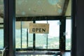 A business sign that says Open on local businesses hang on door at entrance. Say Welcome. Open and closed flip sign in front of