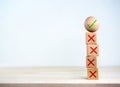 Green correct check mark icon on wood sphere on top, among many red wrong or cross symbol on wooden cube block.