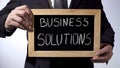 Business solutions written on blackboard, businessman holding sign, strategy Royalty Free Stock Photo