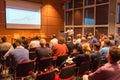 Business speaker giving a talk in conference hall.