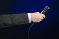 Business speech and topic: a man in a black suit holding a black microphone on a dark blue background in studio isolated Royalty Free Stock Photo