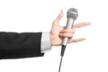 Business and speech topic: Man in black suit holding a gray microphone on an isolated white background in studio Royalty Free Stock Photo