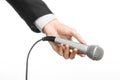 Business and speech topic: Man in black suit holding a gray microphone on an isolated white background in studio