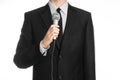 Business and speech topic: Man in black suit holding a gray microphone on an isolated white background in studio Royalty Free Stock Photo