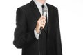 Business and speech topic: Man in black suit holding a gray microphone on an isolated white background in studio Royalty Free Stock Photo