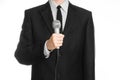 Business and speech topic: Man in black suit holding a gray microphone on an isolated white background in studio Royalty Free Stock Photo