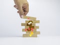 Business startup concept. Hand putting the last piece of wooden block on the top of wood stack to arrange the jigsaw puzzle. Royalty Free Stock Photo