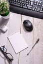 Business still life: a home flower, a white notepad, glasses and a black pen on the table next to a black computer keyboard and a Royalty Free Stock Photo