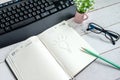 Business still life: a light bulb, a computer keyboard, a desktop flower and black glasses are drawn in pencil on the table in the