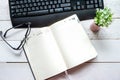 Business still life: a working notebook on the table and a computer keyboard, glasses and a desktop flower