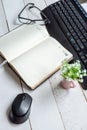 Business still life: a working notebook on the table and a computer keyboard and mouse, glasses and a desktop flower