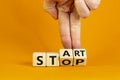 Business and stop or start concept.Male hand flips a wooden cube and changes the word `stop` to `start`. Beautiful orange