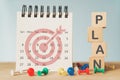 Business strategy, target, goal, monthly planning concept. White calendar with dartboard icon and plan text on wood cube block