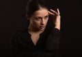 Business strong thinking woman with natural makeup looking with fingers near the face  in black t-shirt on dark shadow black Royalty Free Stock Photo