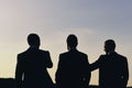 Business and success concept. Silhouettes of men standing against sunset. Leaders discuss project.