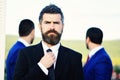 Business success and confidence concept. Businessman with beard adjusts tie