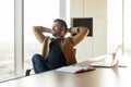 Contented Businessman Relaxing Holding Hands Behind Head Sitting In Office