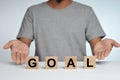 Business success for goal concept. Wooded cube block on a person standing as a background with word goal