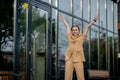 Business success - Happy young business woman celebrating work career achievements with both hands up against office building Royalty Free Stock Photo