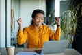 Business success. Overjoyed black woman using laptop and gesturing yes, shaking fists celebrating big luck Royalty Free Stock Photo