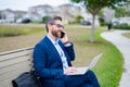 Business talk. Businessman talk on phone sitting on a bench in park. Businessman in suit call phone outside. Businessman Royalty Free Stock Photo