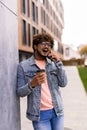 Business talk on a go. Confident young man in glasses holding coffee cup and talking on mobile phone while walking outdoors Royalty Free Stock Photo