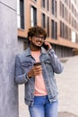 Business talk on a go. Confident young man in glasses holding coffee cup and talking on mobile phone while walking outdoors Royalty Free Stock Photo