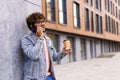 Business talk on a go. Confident young man in glasses holding coffee cup and talking on mobile phone while walking outdoors Royalty Free Stock Photo