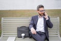 Business talk. Business man talk on phone sitting on a bench in park. Man in suit call phone outside. Handsome business Royalty Free Stock Photo