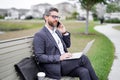 Business talk. Business man talk on phone sitting on a bench in park. Man in suit call phone outside. Handsome business Royalty Free Stock Photo