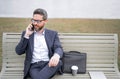 Business talk. Business man talk on phone sitting on a bench in park. Man in suit call phone outside. Handsome business Royalty Free Stock Photo