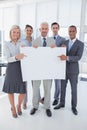 Business team holding large blank poster and smiling at camera Royalty Free Stock Photo