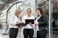 Business team with tablets posing outside office building. Three ladies looking directly on tablet screen Royalty Free Stock Photo