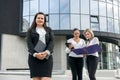 Business team. Three women in suits with folders and tablet posing outside building Royalty Free Stock Photo