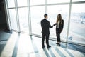 Business, teamwork, partnership, cooperation and people concept - business people shaking hands over panoramic office Royalty Free Stock Photo