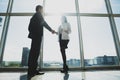 Business, teamwork, partnership, cooperation and people concept - business people shaking hands over panoramic office windows Royalty Free Stock Photo