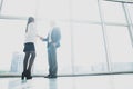 Business, teamwork, partnership, cooperation and people concept - business people shaking hands over panoramic office windows Royalty Free Stock Photo