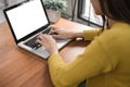 Woman hands typing laptop computer with blank screen on table in coffee shop. Blank laptop screen mock up for display of design. Royalty Free Stock Photo