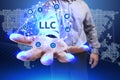 Business, Technology, Internet and network concept. Young businessman shows the word on the virtual display of the future: LLC Royalty Free Stock Photo