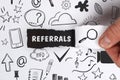 Business, Technology, Internet and network concept. Young businessman shows the word: Referrals