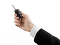 Business theme: car salesman in a black suit holding a car key isolated on white background